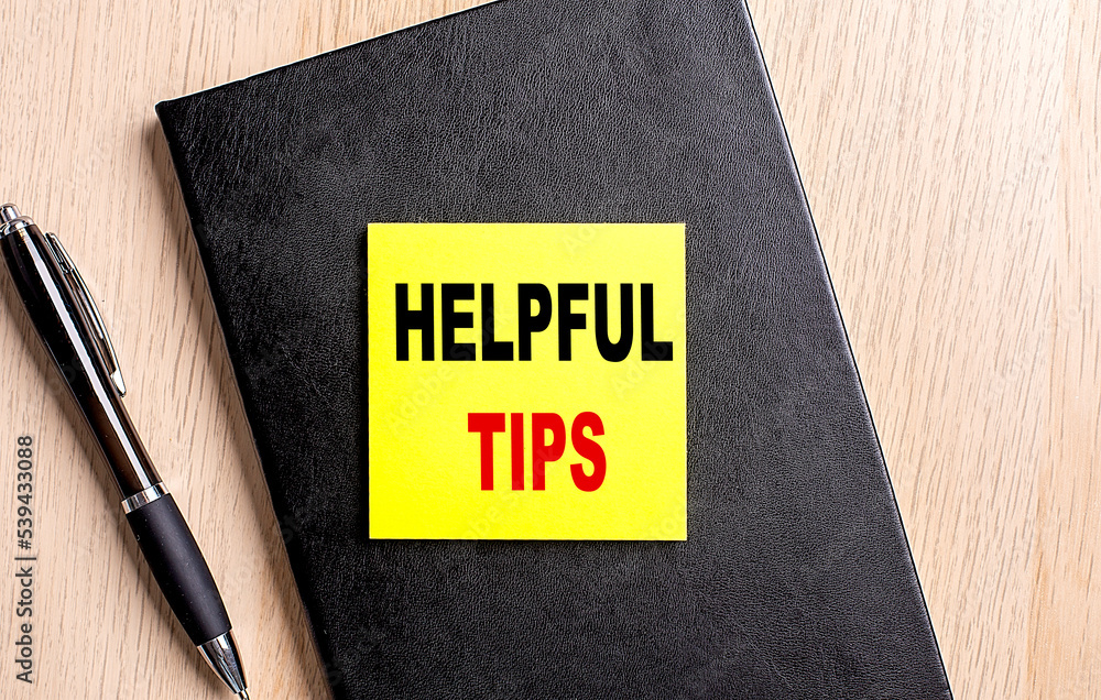 Poster helpful tips text on a sticky on black notebook with pen