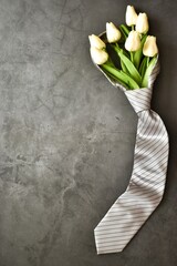 Men's necktie with white tulips on gray background. Copy space. Flat lay, top view. Fathers day,...