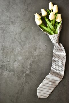Men's necktie with white tulips on gray background. Copy space. Flat lay, top view. Fathers day, Boss day, mens day, valentine's day for holiday banner. Template for Greeting card. Vertical Banner