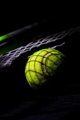 Tennis racket on tennis ball with strong contrast chiaroscuro light effect with dark shadows
