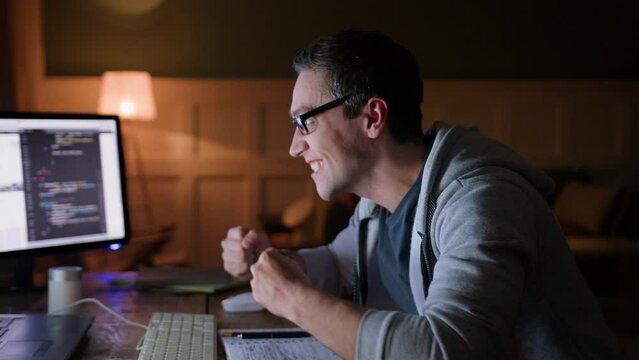 young man remote works sitting at table with computer laptop in darkness. waits nervously, gets excited of great news, stands up, screams yeah and laughs, gestures emotionally 