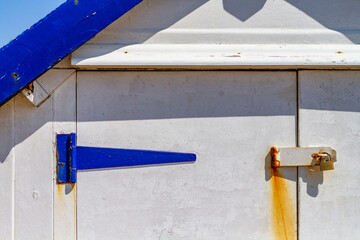 Close up of blue and white beach hut with rusty lock