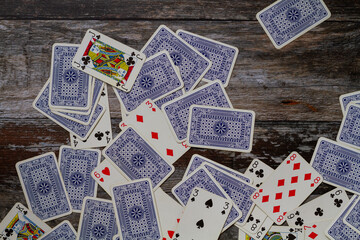 Old blue playing cards scattered on a rustic wooden surface, some face up