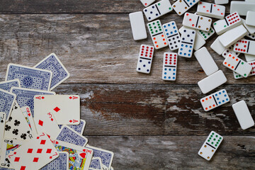 Scattered playing cards and dominoes on a rustic wooden surface