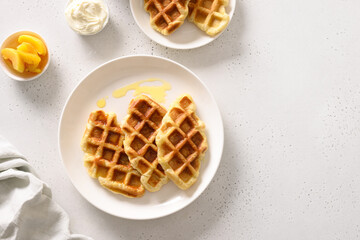 Popular croffles with mango for delicious breakfast on white background. Croissant as waffle. View from above. Copy space.