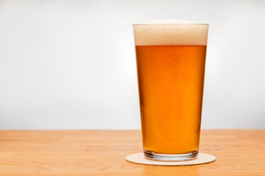 Full shaker pint glass of ale or beer on a table