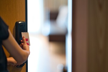 Female hand holding a keycard and opening hotel room door on sunny day