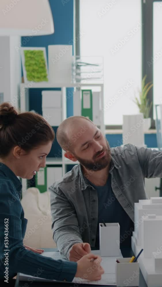 Poster vertical video: colleagues doing teamwork in designing blueprints plan after analyzing building mode