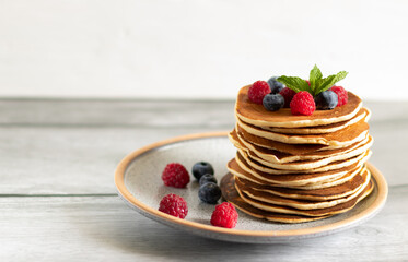 Pancakes with raspberries, blueberries on a light background with a copy space