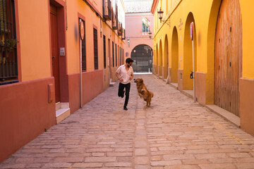 handsome, young Hispanic man with his brown golden retriever dog, running through the streets of a European city while having fun. Concept pets, animals, dogs, pet love, golden retriever.