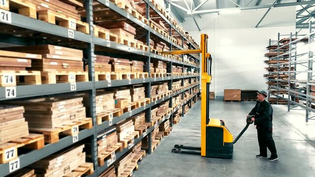 Warehouse for storage. The engineer uses a forklift to remove pallets with goods from the shelves.