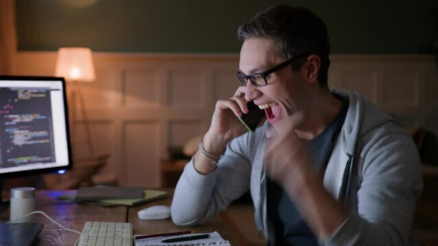 young man remote works sitting at table with computer laptop in darkness. waits nervously, gets excited of great news, spins around on chair, screams yeah and laughs, gestures emotionally 