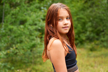 Naklejka premium Young attractive female doing yoga on the mat in the forest. Red-haired teenager doing warrior asana. Active sport outdoors.
