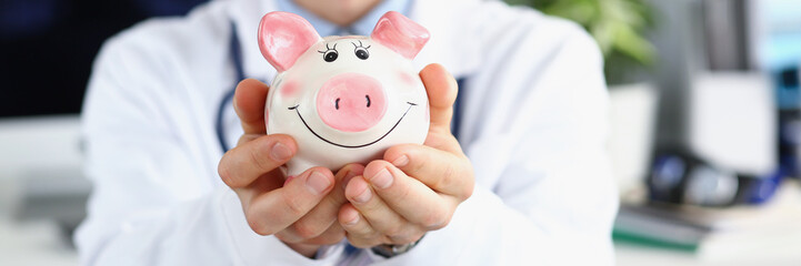 Man doctor hold white piggy bank, message to saveup money for healthcare