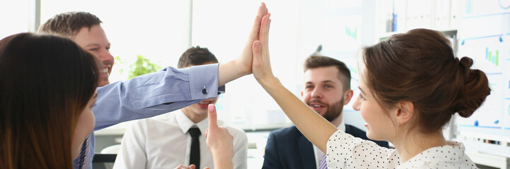 Colleagues give high five gesture in order to celebrate end of company project