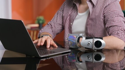 Cropped shot of man with bionic arm work on computer at home.
