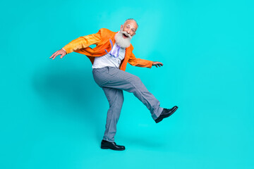 Full length photo of sweet funny pensioner guy wear neon orange jacket dancing disco walking isolated teal color background