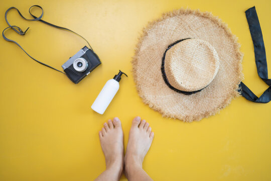 Summer vacation items and accessories. suntan cream, camera and sun hat on yellow background. Top view flat lay with copy space.