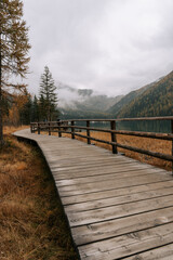 Wanderweg / Holzsteg am Antolzer See in den Dolomiten. Herbstliche Landschaft am See in Südtirol. Regnerisches Wetter 3