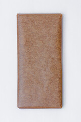 Closeup of chocolate bar in blank craft paper packaging. Mockup isolated on a gray background