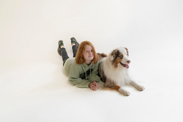 Fototapeta na wymiar Redhead girl Teenager 11-12 years old and Australian Shepherd Dog, child in casual clothes and a purebred aussie dog.