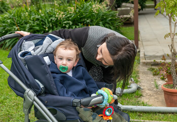 Baby on stroller with pacifier outdoor with his mother