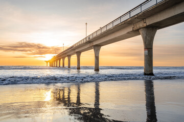 Beautiful sunrise at New Brighton Pier, Christchurch, New Zealand. It is one of eastern country's main entertainment and tourist centers, with its architecturally unique pier and scenic coastline. - obrazy, fototapety, plakaty