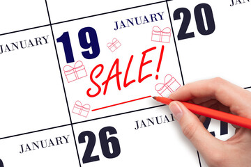 Hand writing text SALE and drawing gift boxes on calendar date January 19. Shopping Reminder