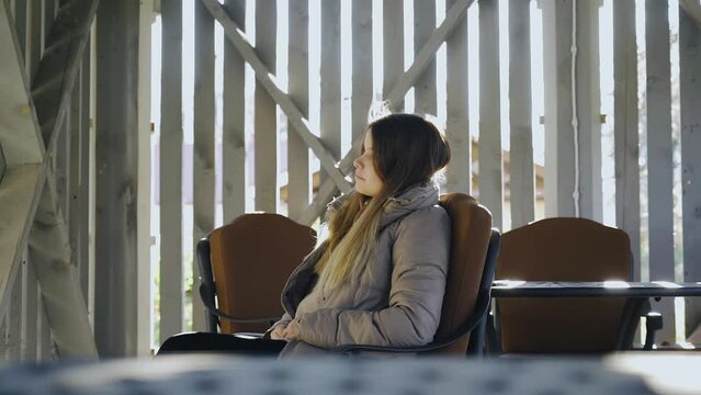 On a bright autumn day, the girl is resting sitting on a chair on the veranda. Very cool light