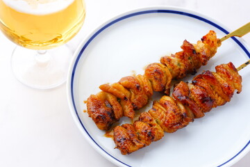 炭火焼にしたタレの焼き鳥（とり皮）をつまみにビールを飲む