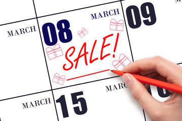 Hand writing text SALE and drawing gift boxes on calendar date March 8. Shopping Reminder