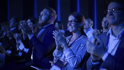 Young Female Sitting in a Crowded Audience at a Science Conference. Delegate Cheering and Applauding After an Inspirational Keynote Speech. Auditorium with Young Successful Specialist.