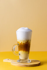 Pumpkin Spice Latte in a Glass Mug with Cinnamon on Wooden Cutting Board Tasty Autumn Drink Yellow Background Vertical