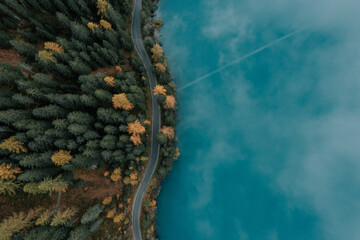 Antholzer See im Herbst. See im Herbst mit der Drohne fotografiert. Straße durch den Wald am See. Herbstfarben und blauer See