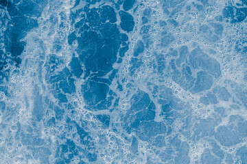 Abstract blue sea water with white foam and bubbles for background, natural summer background