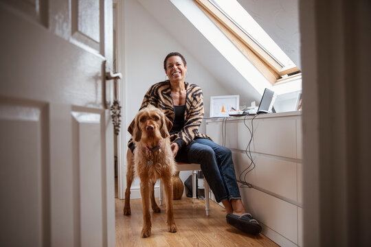 Portrait happy woman with dog in home office