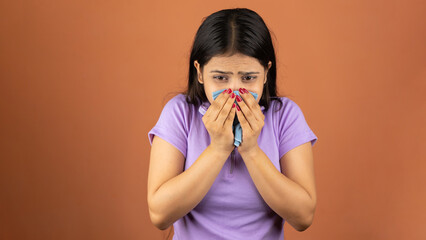 Young woman sneezing into a handkerchief because of her allergy or cold, isolated over color...