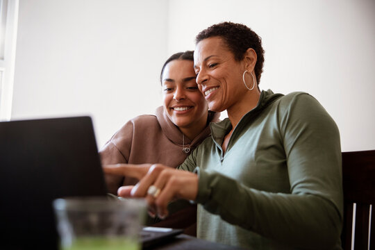 Happy Mother And Young Adult Daughter Using Laptop