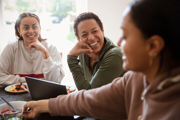 Happy mother and young adult daughters talking at home