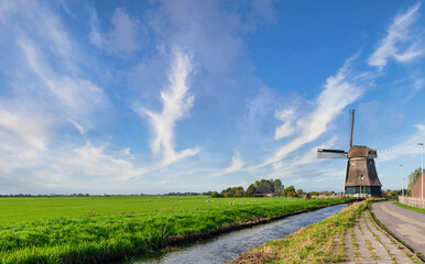 historic windmill in lush green dutch landscape under blue sky