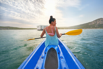 Woman with oar kayaking on sunny summer lake