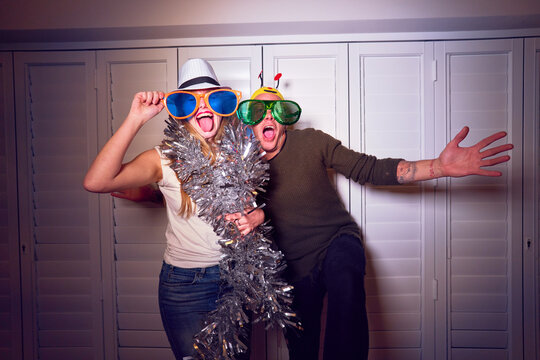 Portrait happy, playful couple in silly oversized eyeglasses