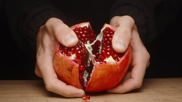 I peel the pomegranate fruit. I tear it into slices. On a black background. slow motion