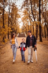 happy family with a child on an autumn walk in the city park walk along the alley, family fun