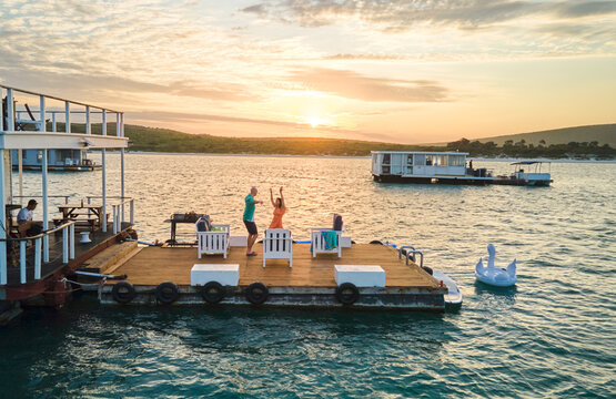 Carefree Couple Dancing On Houseboat Patio On Lake At Sunset