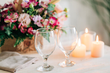 Festive dinner. Celebration table setting with flowers and candles. Beautiful table with glasses for drink and cozy flame lights. Romantic evening details