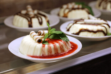 Panna cotta with strawberry jam in a cafe. Sweet cream dessert decorated with fresh leaves