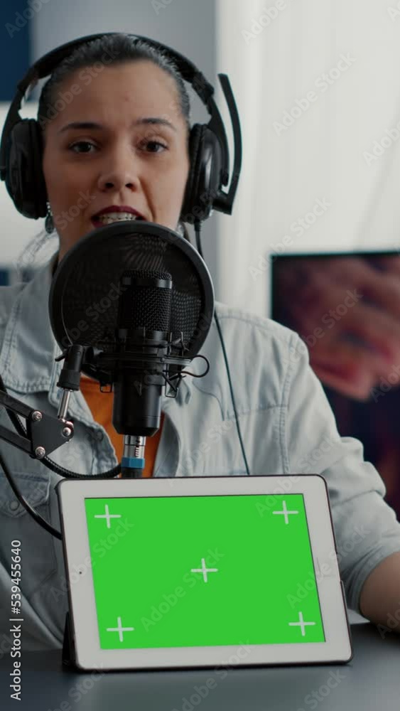 Poster vertical video: influencer in studio promoting product on tablet with green screen display. social m