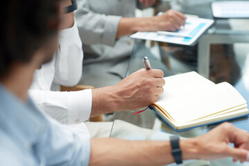 business colleagues taking notes in a notebook.