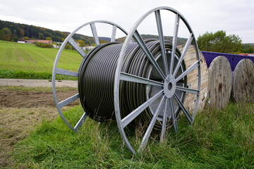 Fiber optic cable black on a cable drum, for laying in a field near Gundelshausen, Bavaria -...